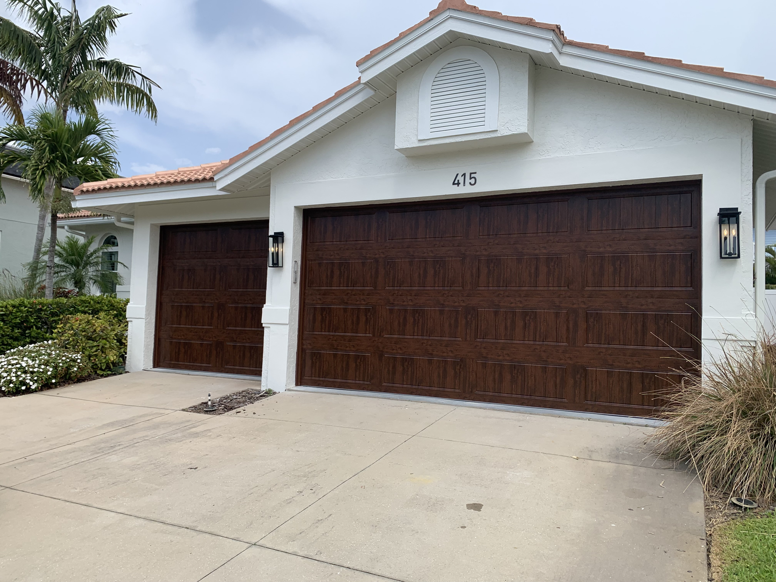 Brown double and single garage doors on a white home