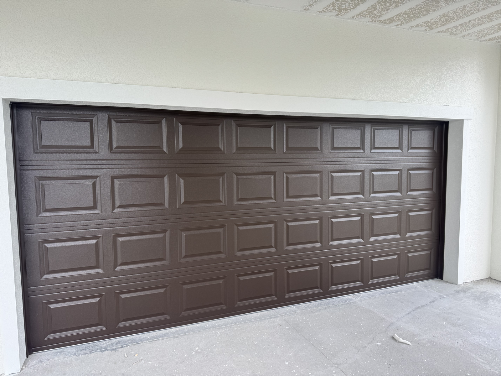 Dark brown raised-panel double garage door in a new build
