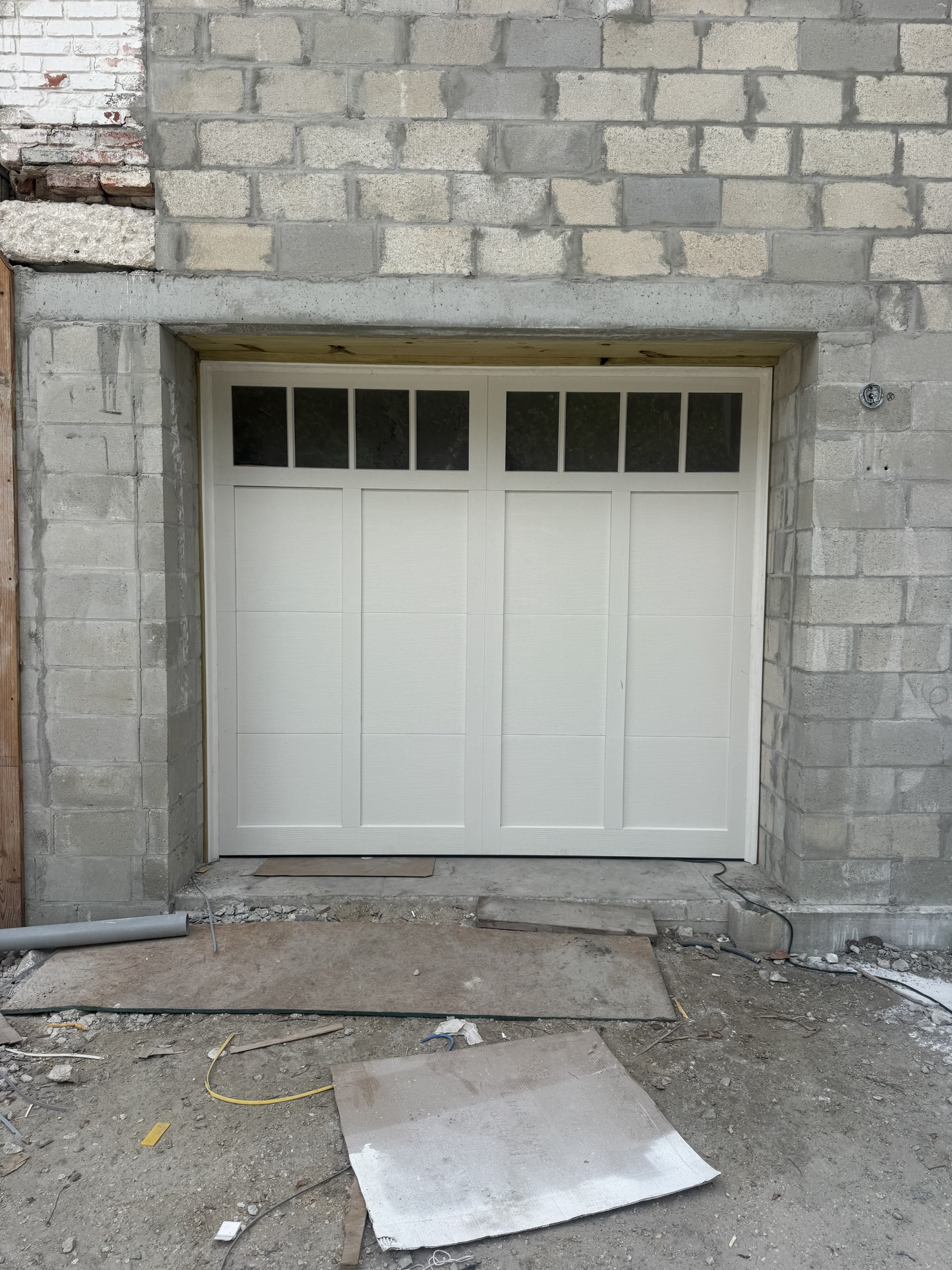 White carriage-style garage door with windows in a block wall