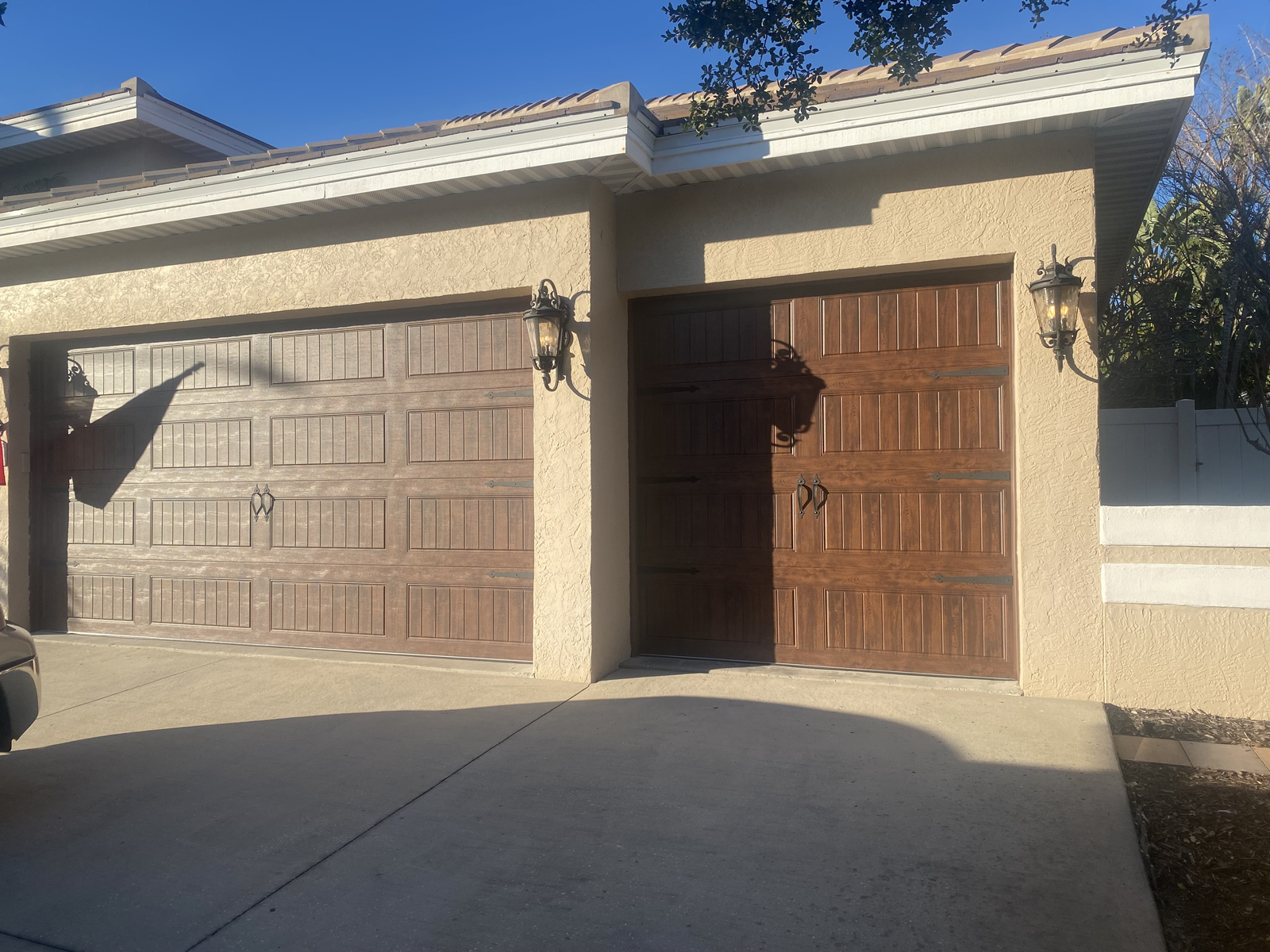 Two brown wood-look garage doors on a tan stucco home